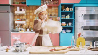 Kyary Pamyu Pamyu in a baker's outfit and chef hat in the retro kitchen set of the Pang Pang Pang visuals.