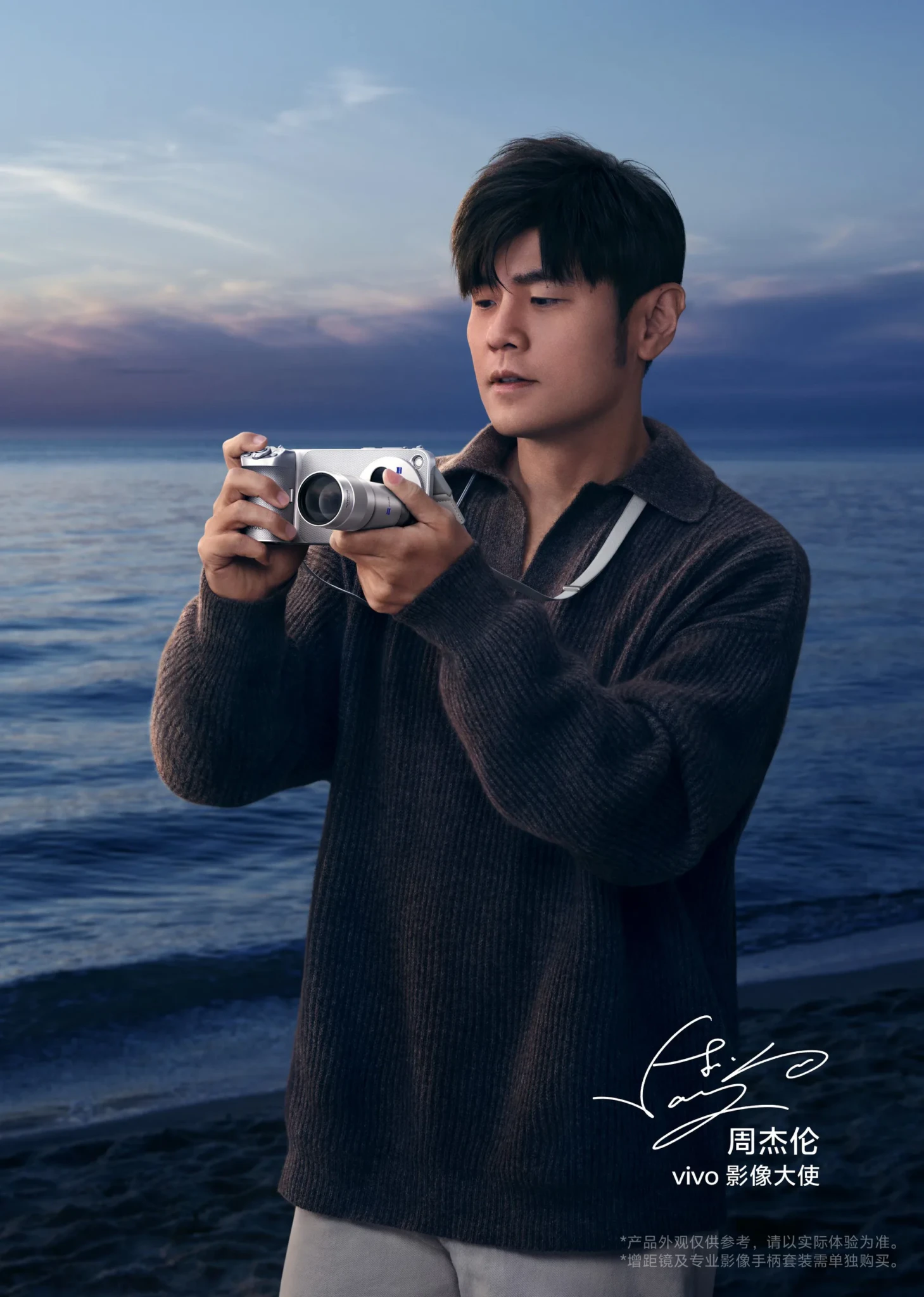 vivo brand ambassador Jay Chou holds a silver vivo camera with a ZEISS lens on a beach at dusk