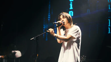 can't be blue performing together with a handheld microphone in front of a glowing blue digital backdrop