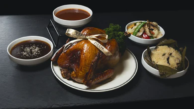 PAUL's Sesame Soy Turkey tied with a gold ribbon, surrounded by sauces, sides and a leaf-wrapped rice parcel