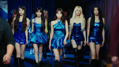 LE SSERAFIM members walking through a dark venue in matching blue metallic outfits