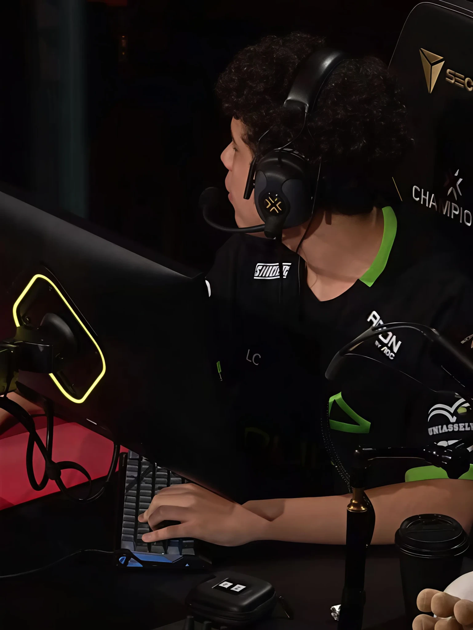 A LOUD player in a black jersey with green trim and a headset with a boom mic types at a VALORANT Champions 2026 station