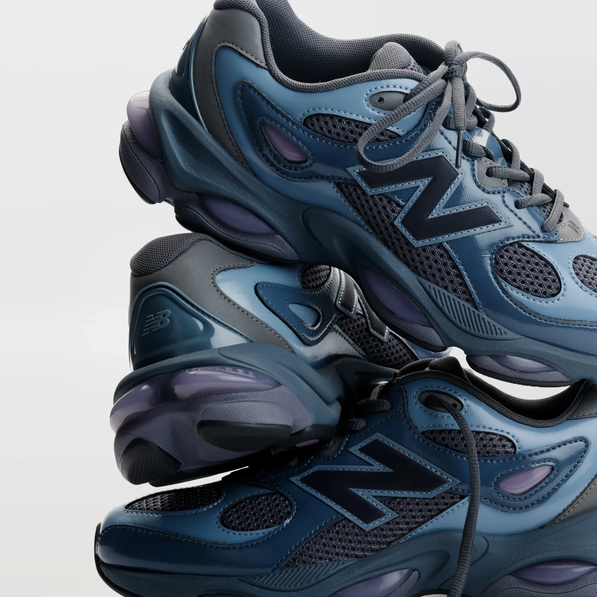Several pairs of the New Balance 983 in dark blue and grey stacked against a light background