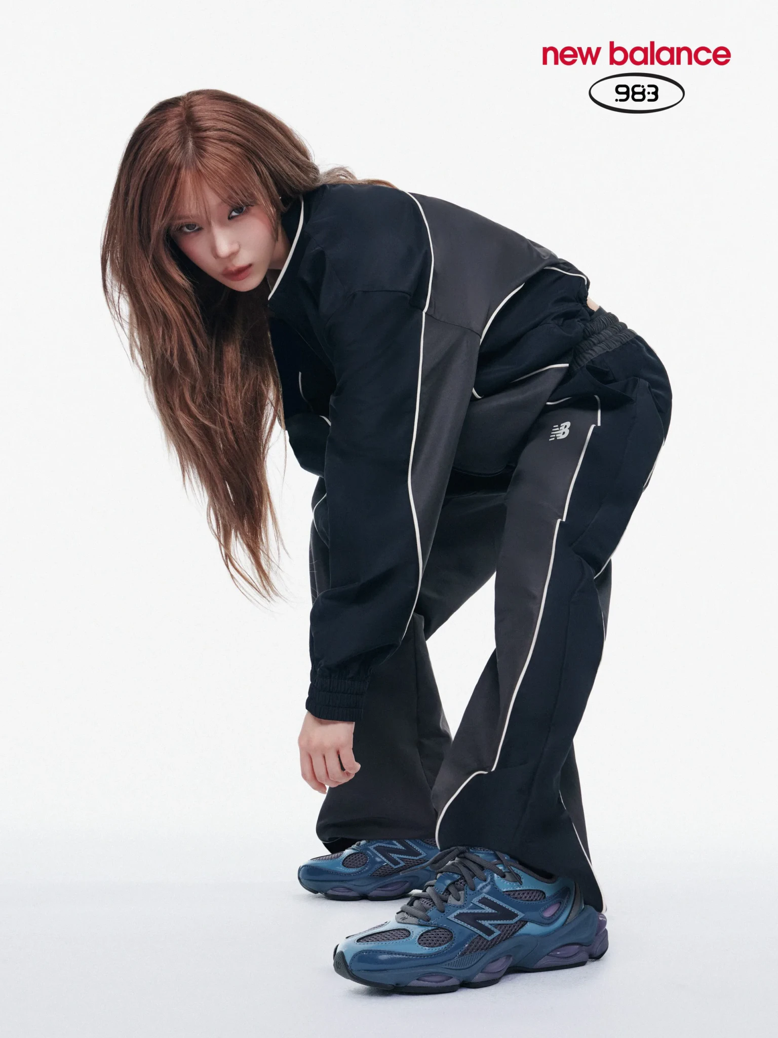 Winter of aespa in a black piped track jacket and pants wearing the New Balance 983 in a studio