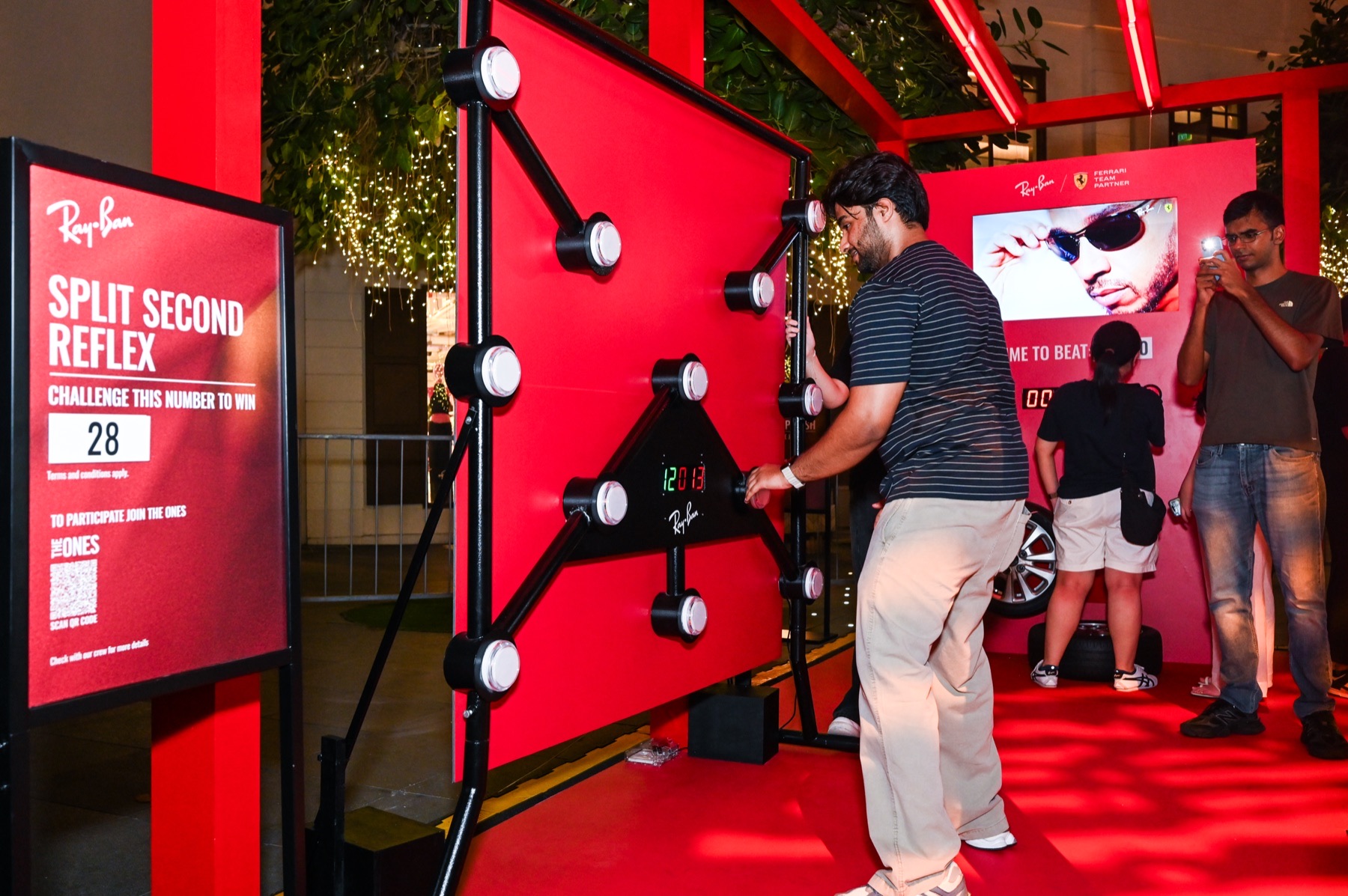 Visitors at the Split Second Reflex challenge, a red wall of lit buttons, at the Ray-Ban Beyond The Track pop-up.