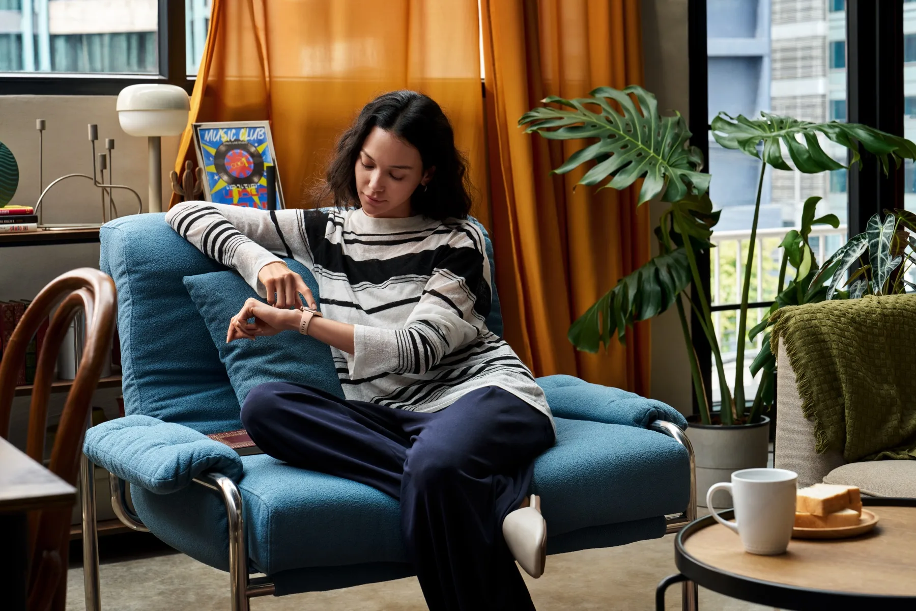 A woman checks her gold HUAWEI WATCH 6 while seated at home.