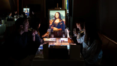 Guests seated at a dining table with a large Mona Lisa print laid across it at Conrad Singapore Marina Bay