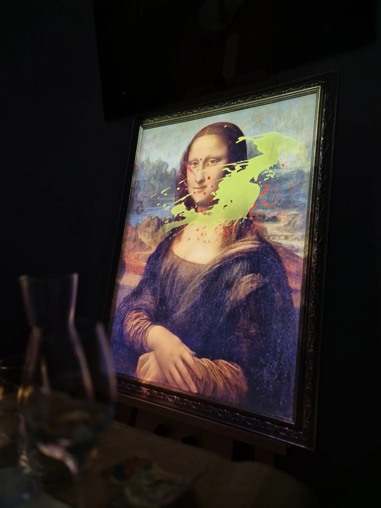 A framed Mona Lisa reproduction splashed with yellow-green and red paint, part of the 7 Paintings dinner at Conrad Singapore Marina Bay