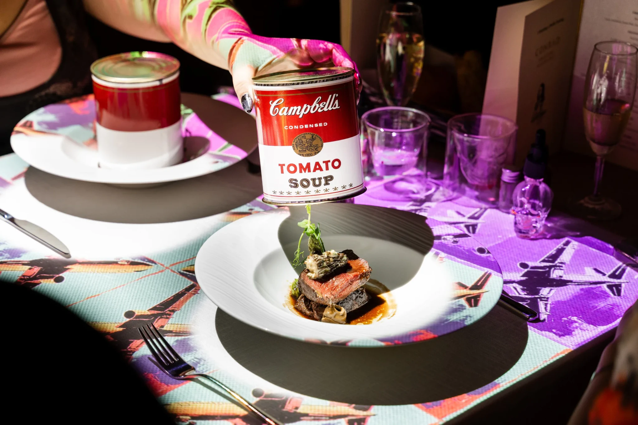 A Campbell's Tomato Soup can held above a plate of Wagyu beef tenderloin with smoked morels at Conrad Singapore Marina Bay