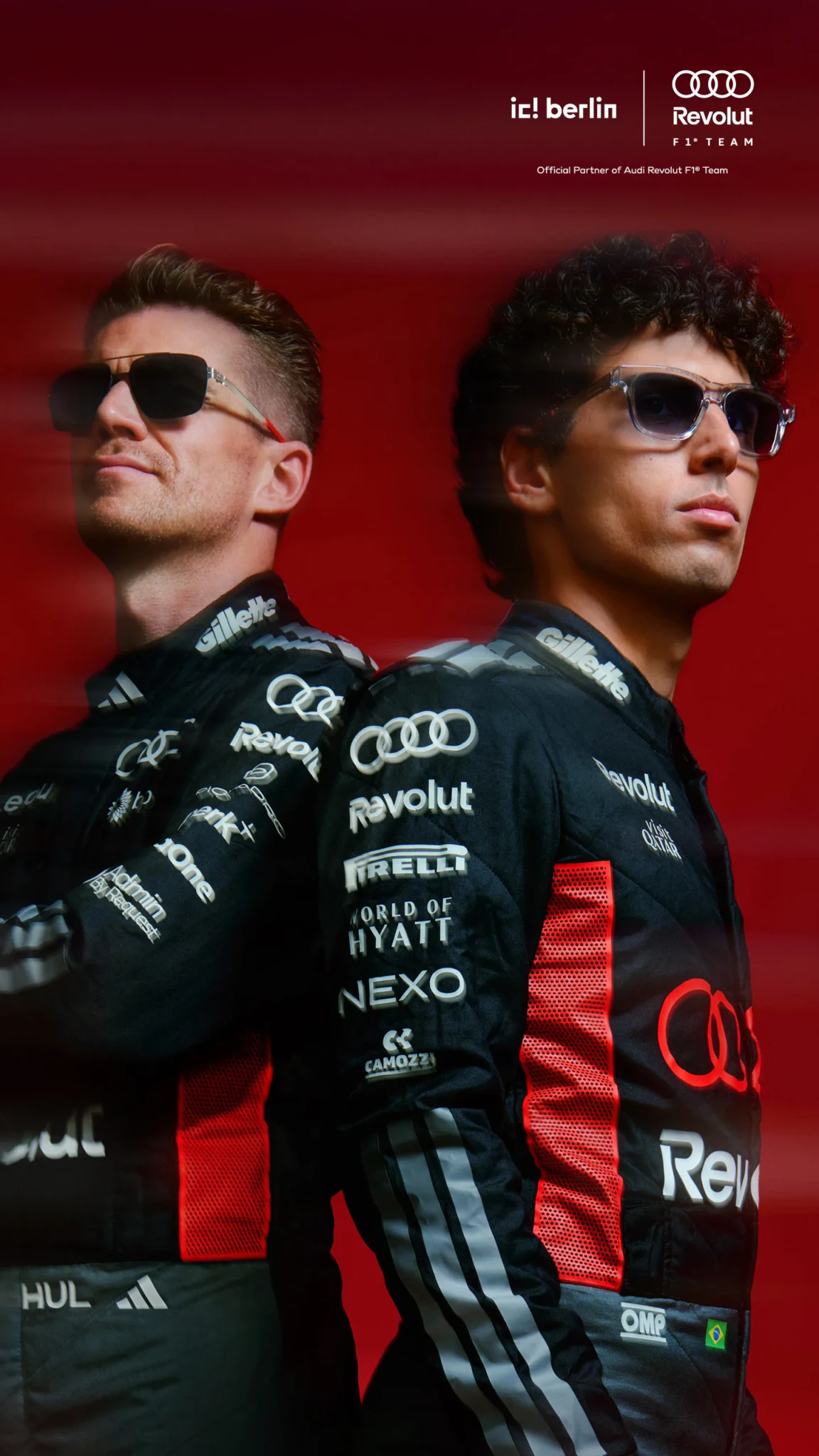Two Audi Revolut F1 Team drivers in black race suits stand back to back against a red background in an ic! berlin campaign photo.