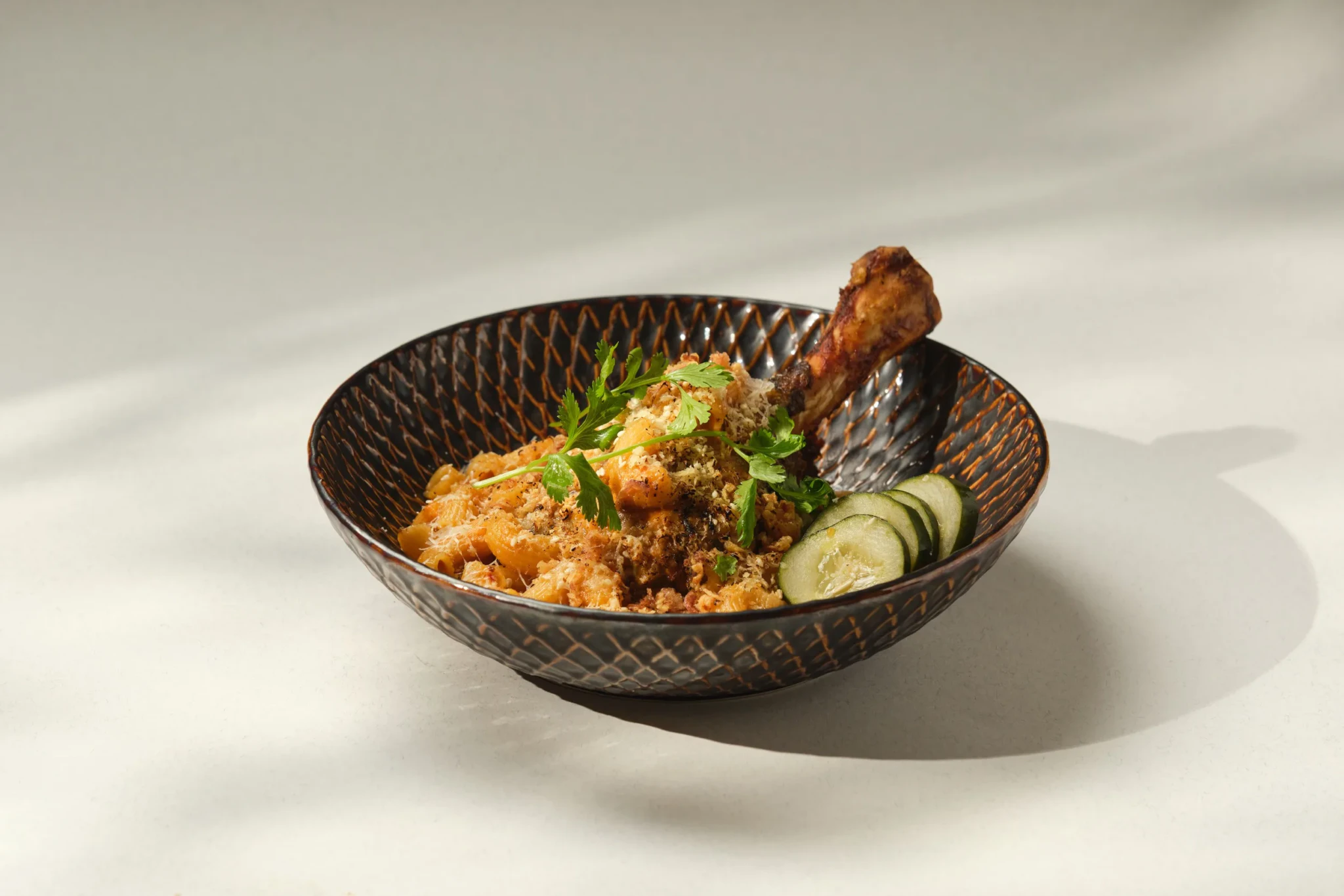 Rendang Lamb Shank Mac & Cheese at PS.Cafe Harding, a lamb shank on baked macaroni with breadcrumbs and sliced cucumber