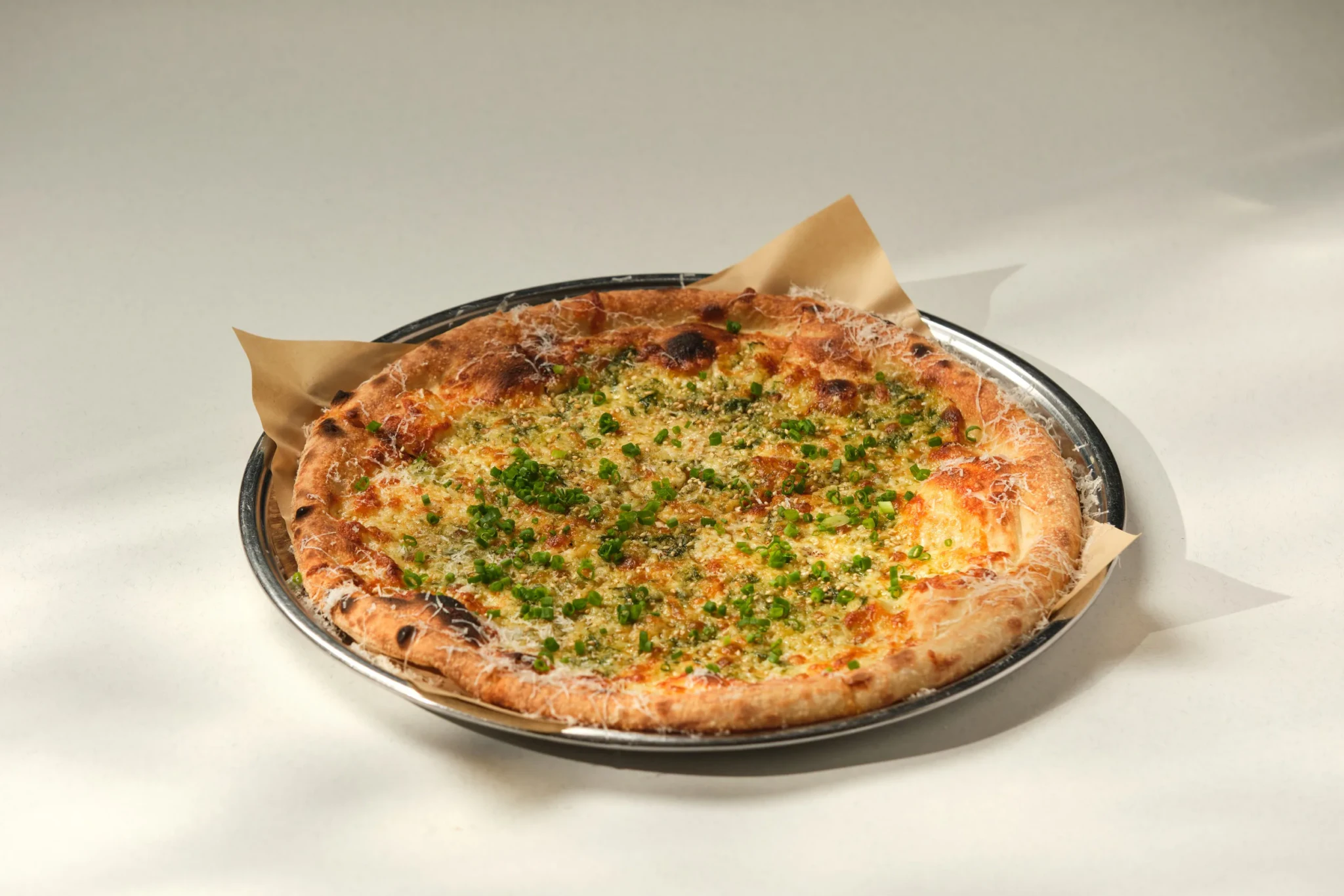 Garlic and Burnt Scallion pizza at PS.Cafe Harding, topped with grated cheese and chopped scallions on a round metal tray