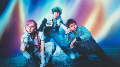 The three members of muque posing in front of a blue and pink light backdrop