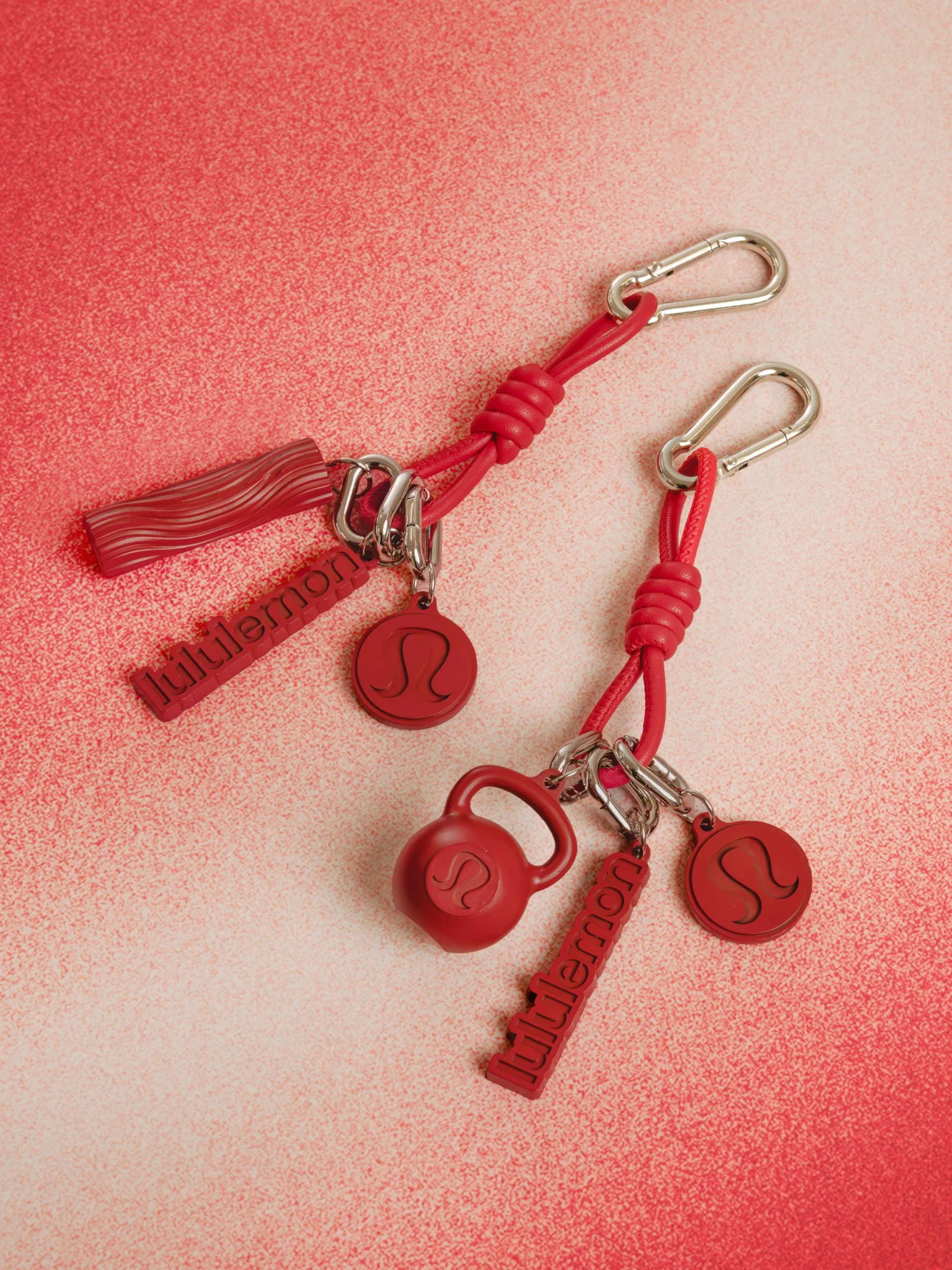 Red lululemon keychain charms including a kettlebell, wordmark tag and round logo disc on silver carabiners