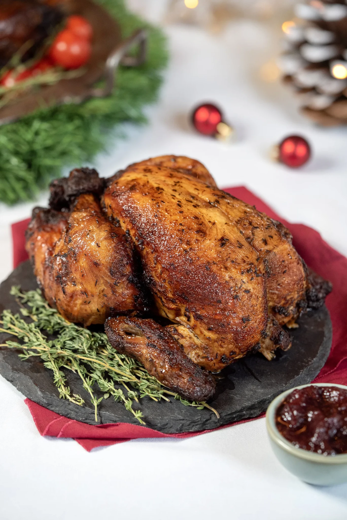 Whole roasted Cajun chicken garnished with thyme on a slate board