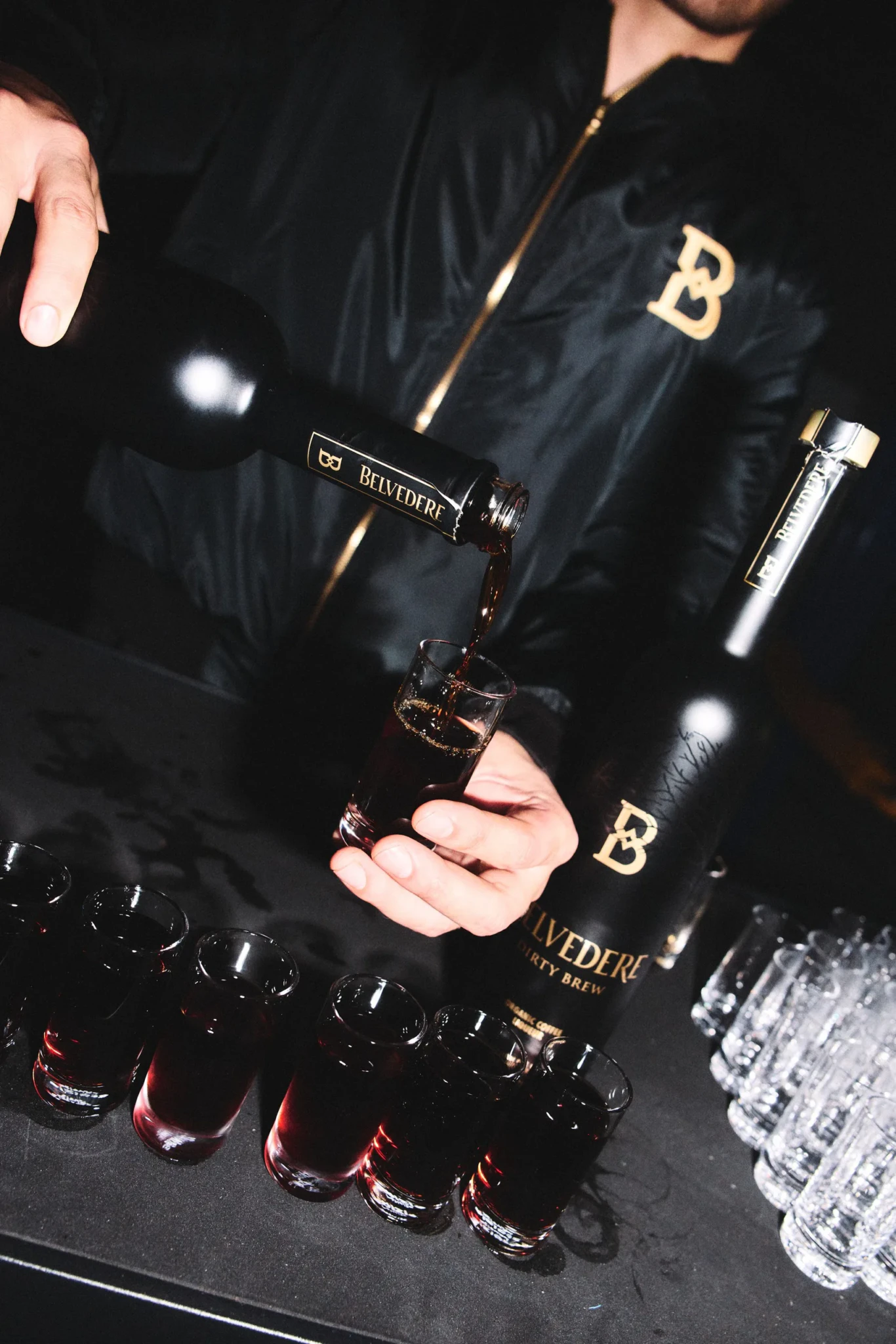A bartender pours Belvedere Dirty Brew from the bottle into a shot glass