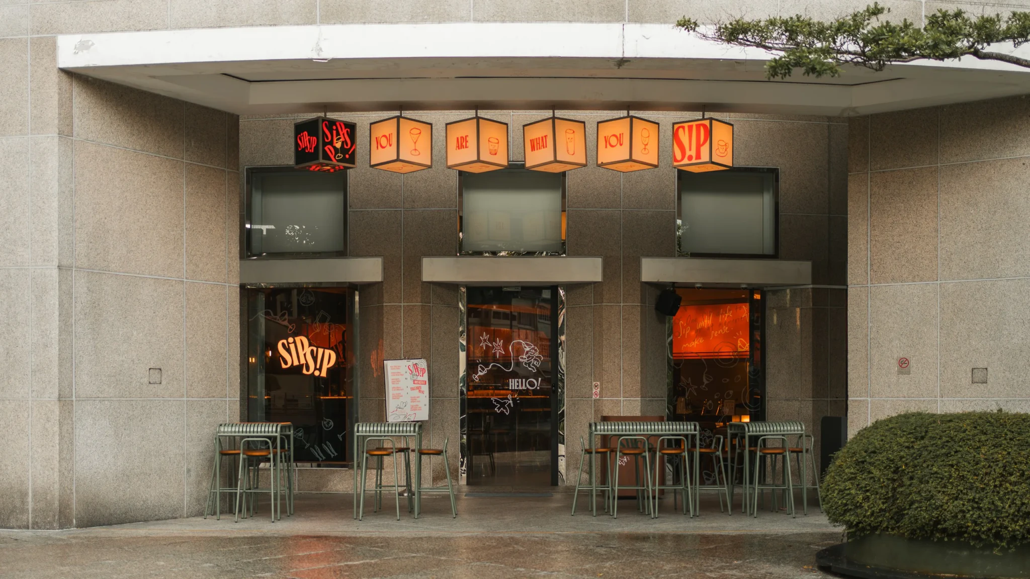 The exterior of Sip Sip with glowing orange cube lanterns reading 