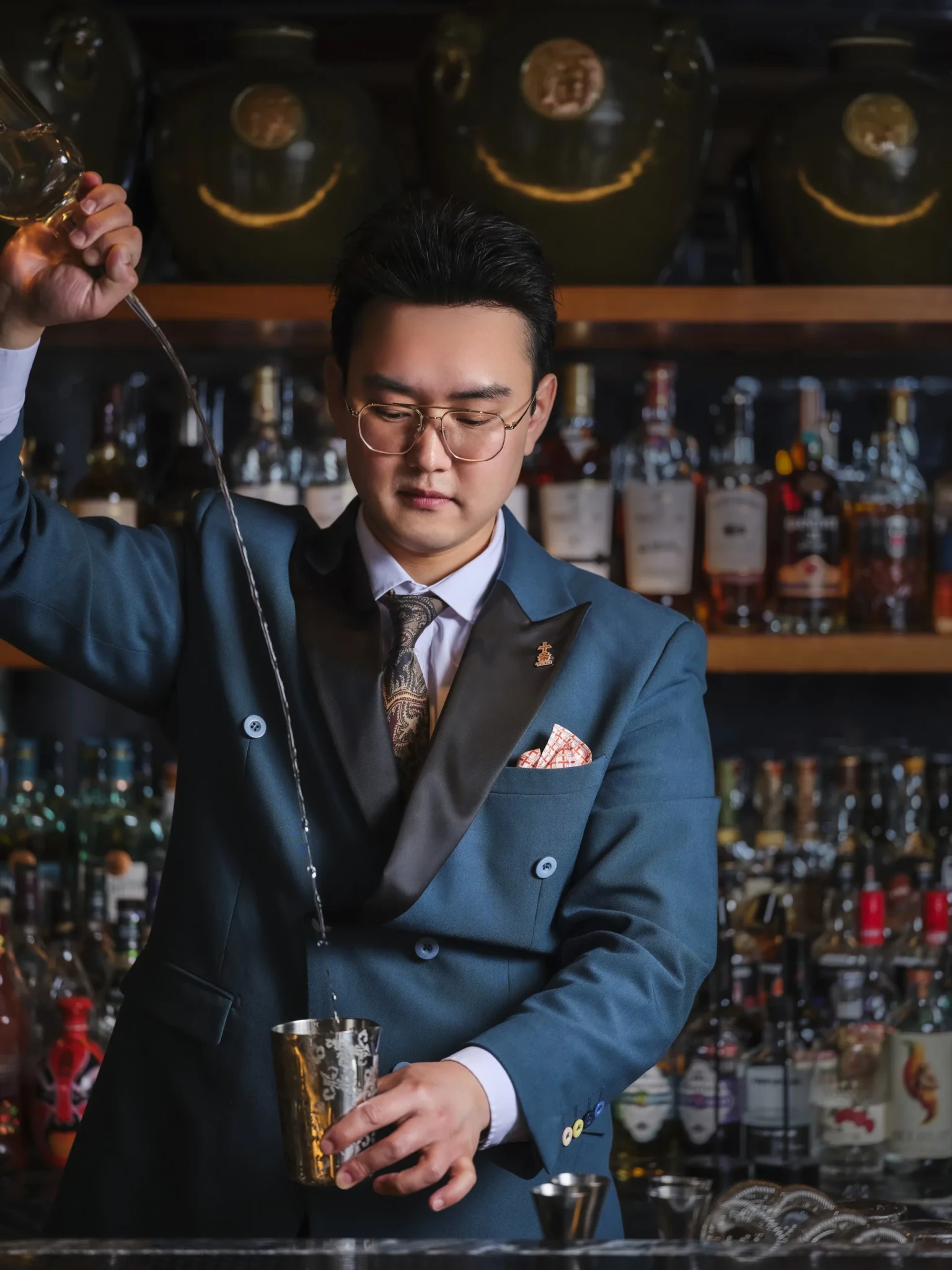 Matt Guo of TIAO pouring from a long-spouted vessel into a silver shaker behind a bar