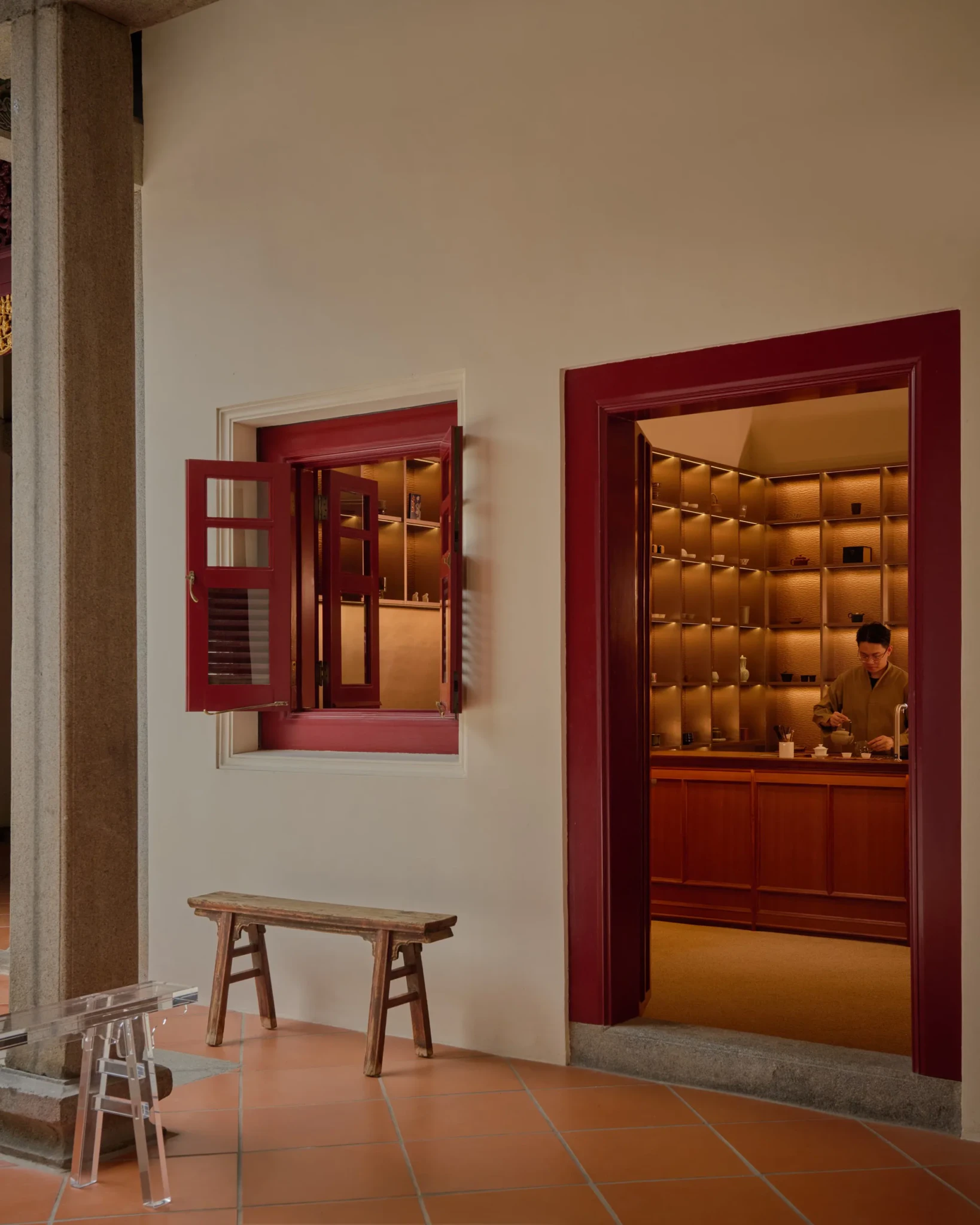A tea session in progress behind a backlit shelf wall beside a red-framed window