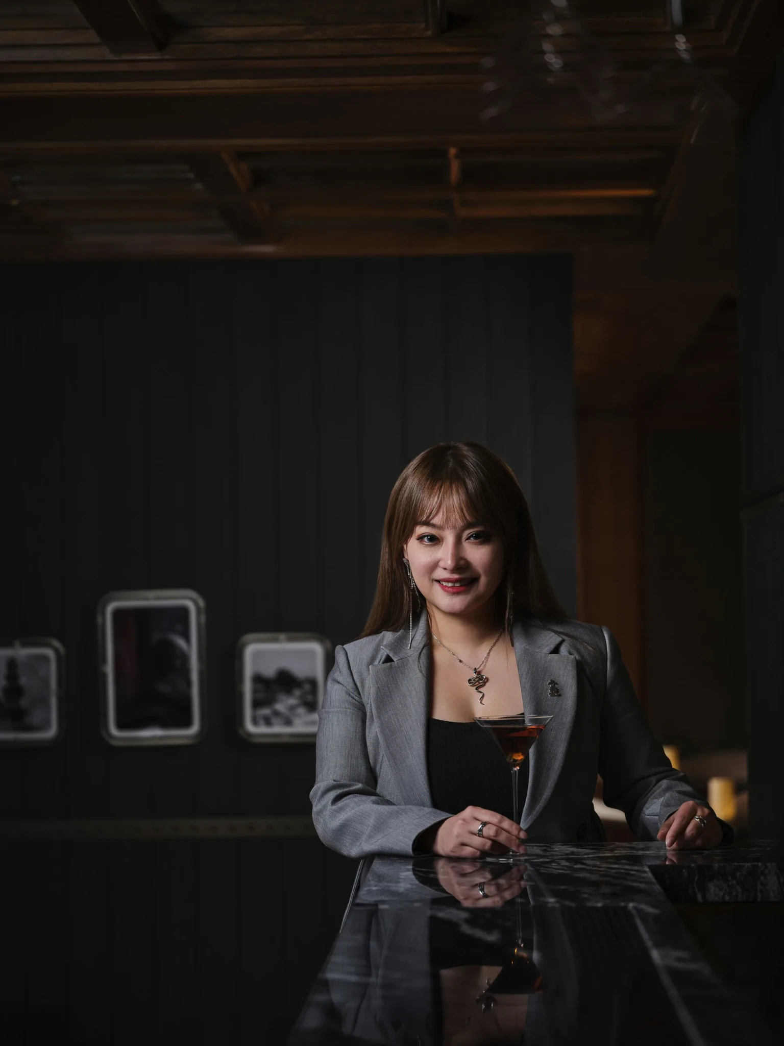 Miranda Xu of TIAO posing behind a bar holding a cocktail