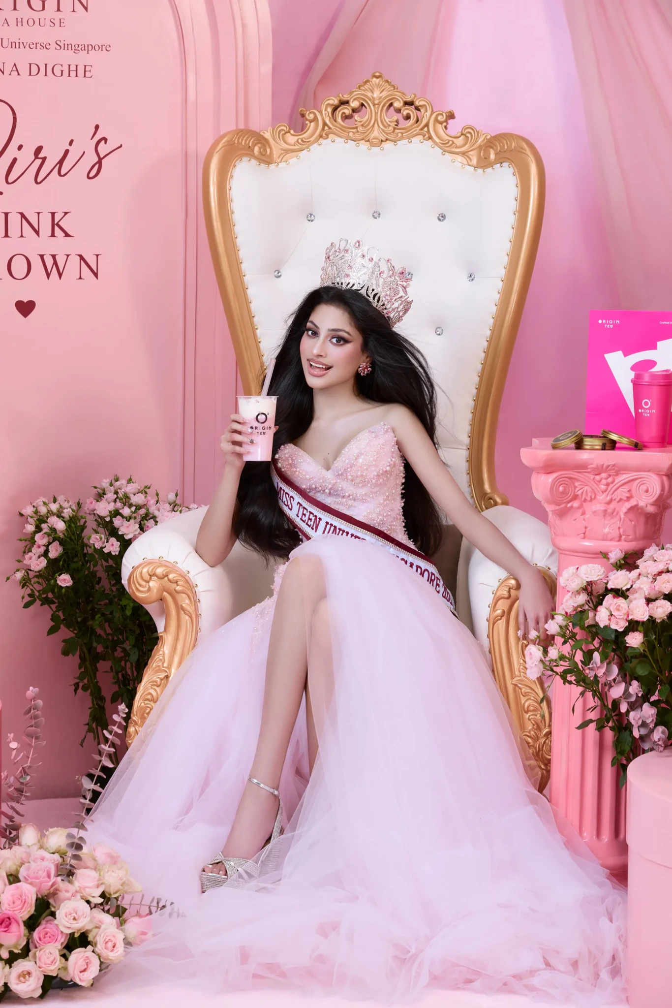 Riona Dighe on a pink throne holding a Riri's Pink Crown drink