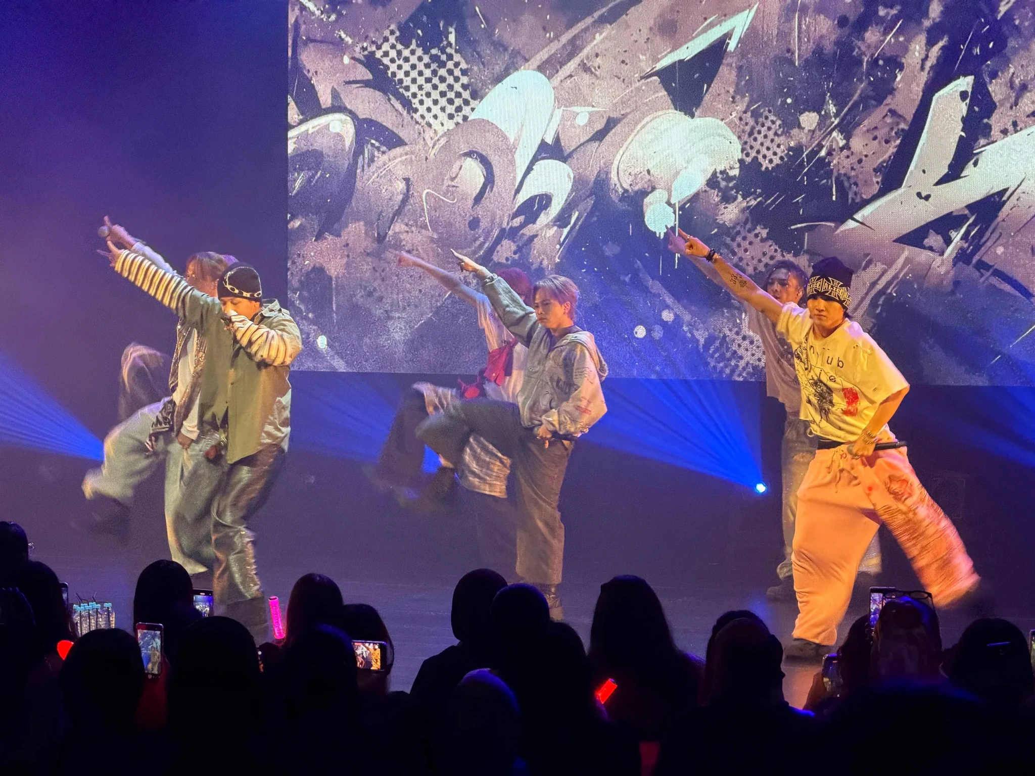 NEO, TAKERU and RYOTA dance at the front of the stage as ONE OR EIGHT perform in front of a graffiti-style rear screen