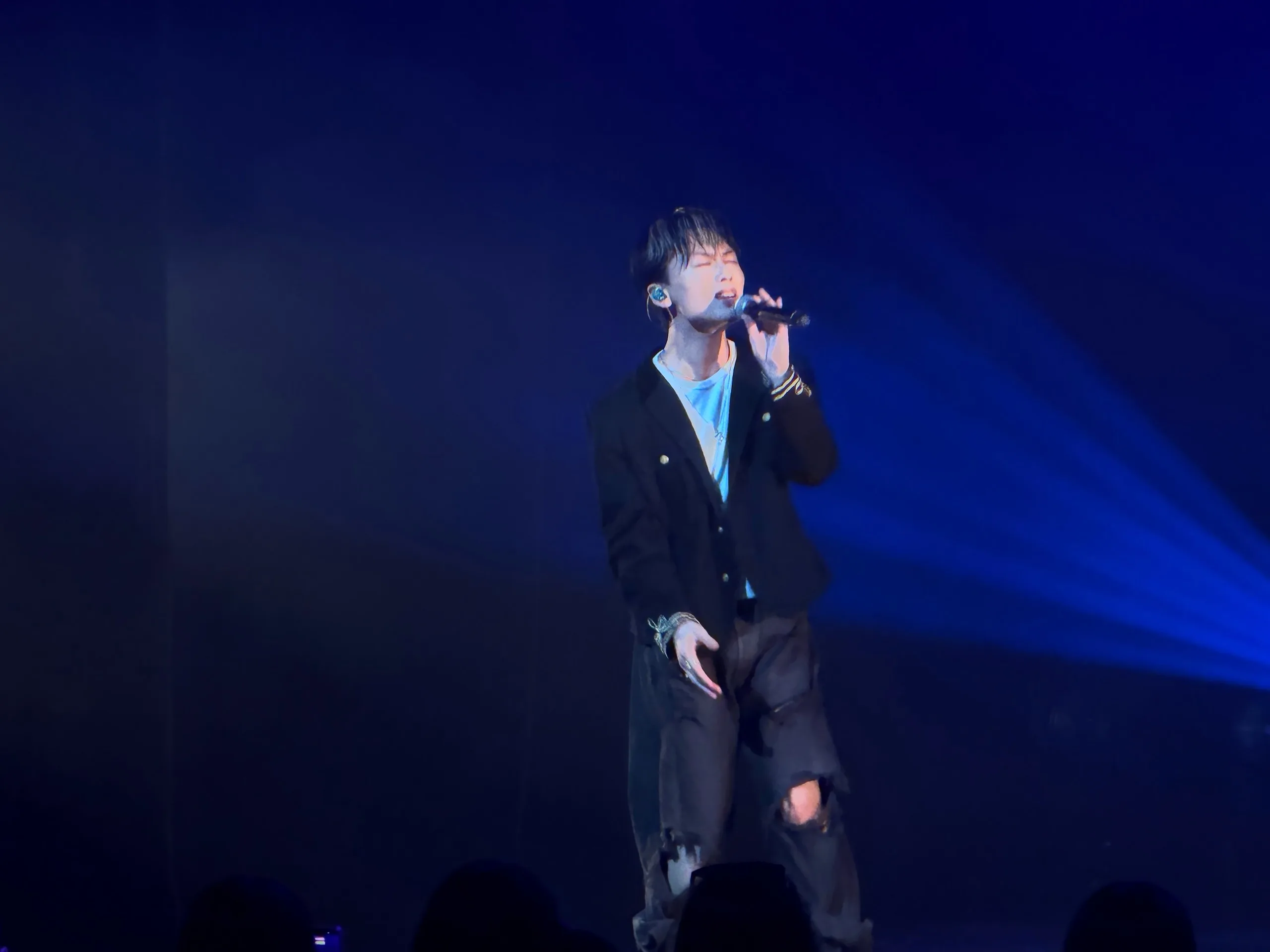 YUGA of ONE OR EIGHT sings with his eyes closed as blue light cuts across the stage