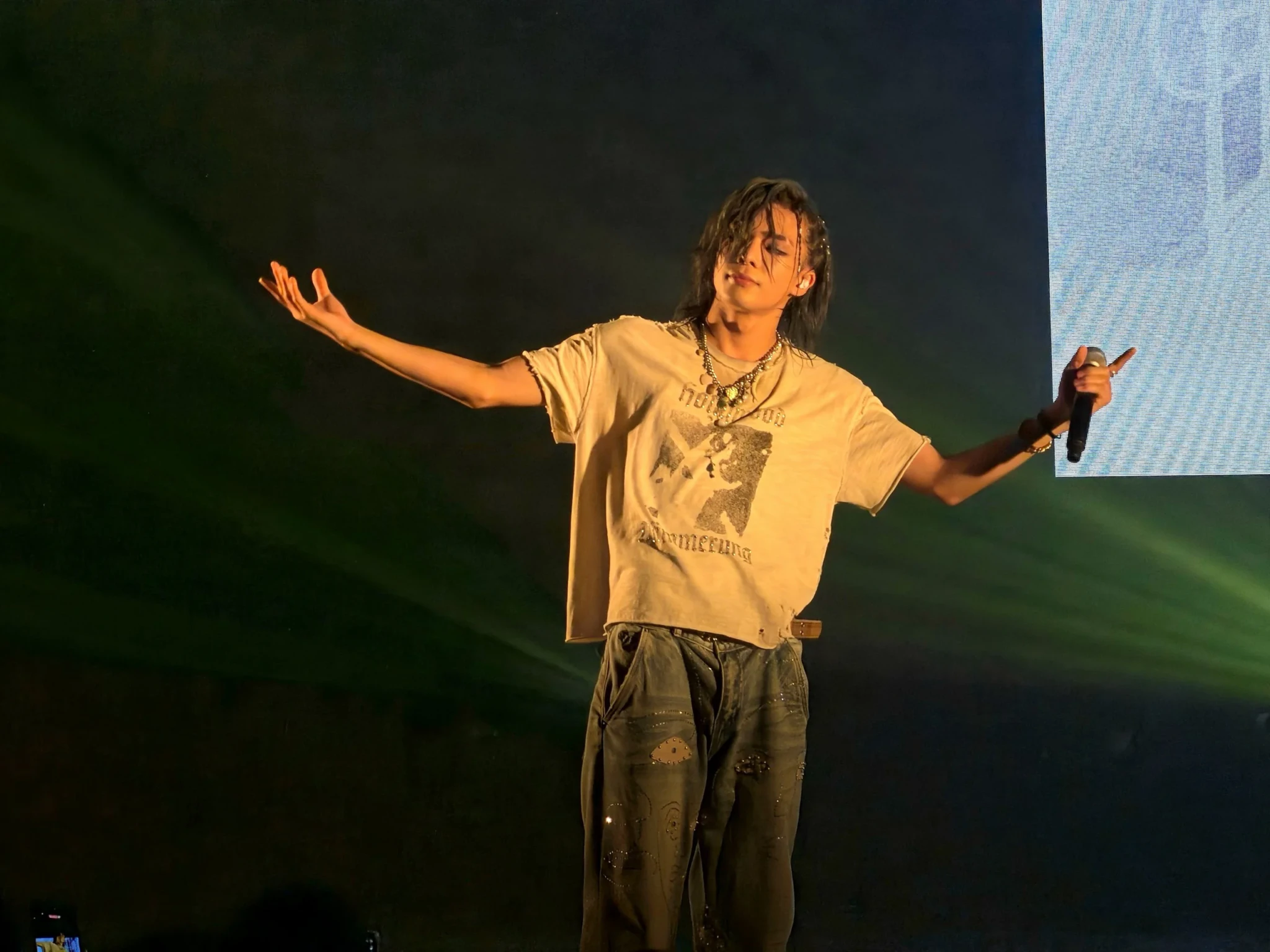 TSUBASA of ONE OR EIGHT opens his arms and closes his eyes with a microphone in hand under warm stage lights