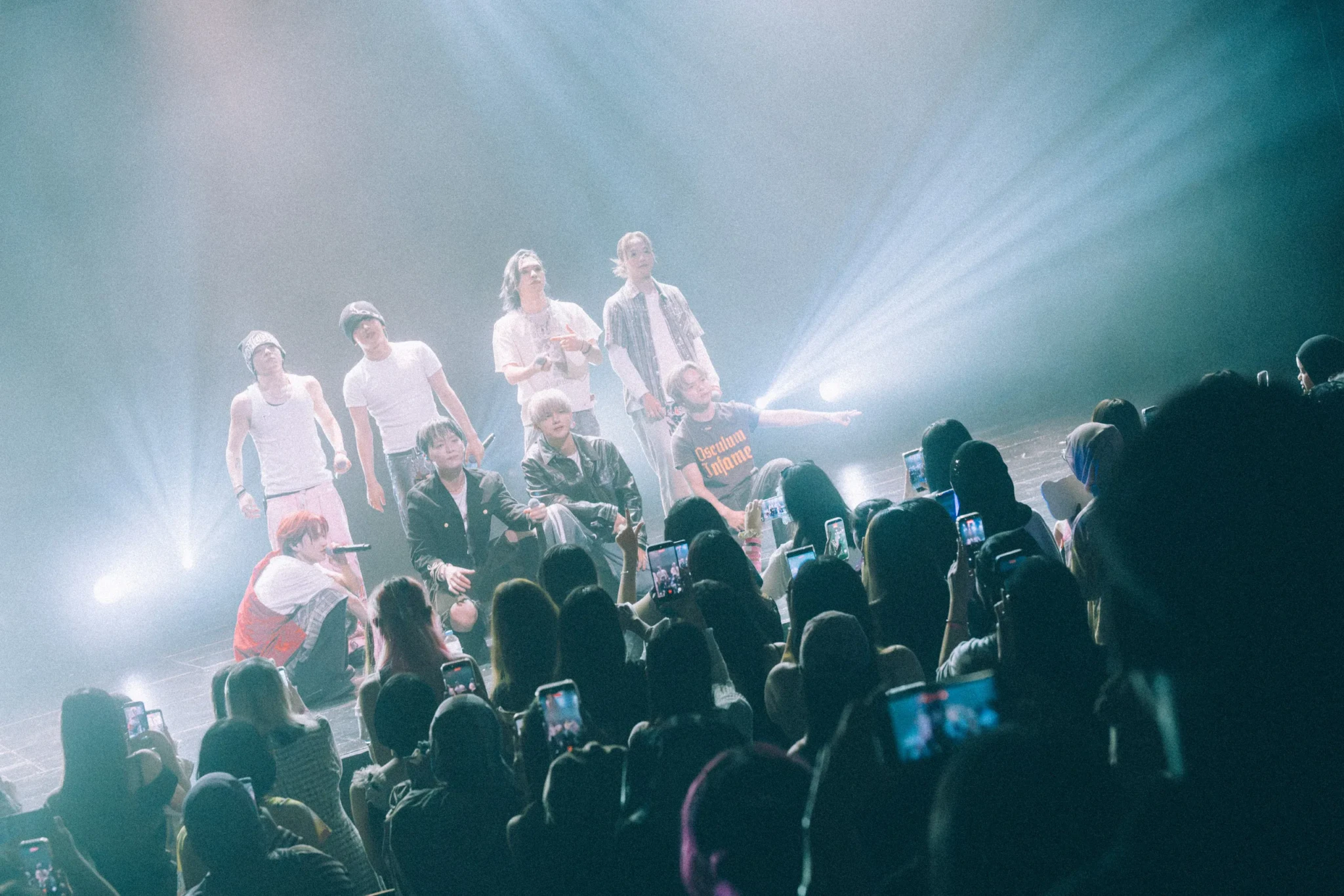The members of ONE OR EIGHT gather and pose at the front of the stage for fans holding up their phones