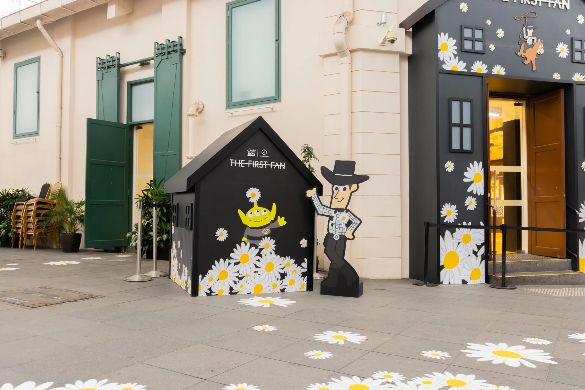 The pop-up storefront with a black daisy-decorated house display featuring a Toy Story Alien and a Woody cutout