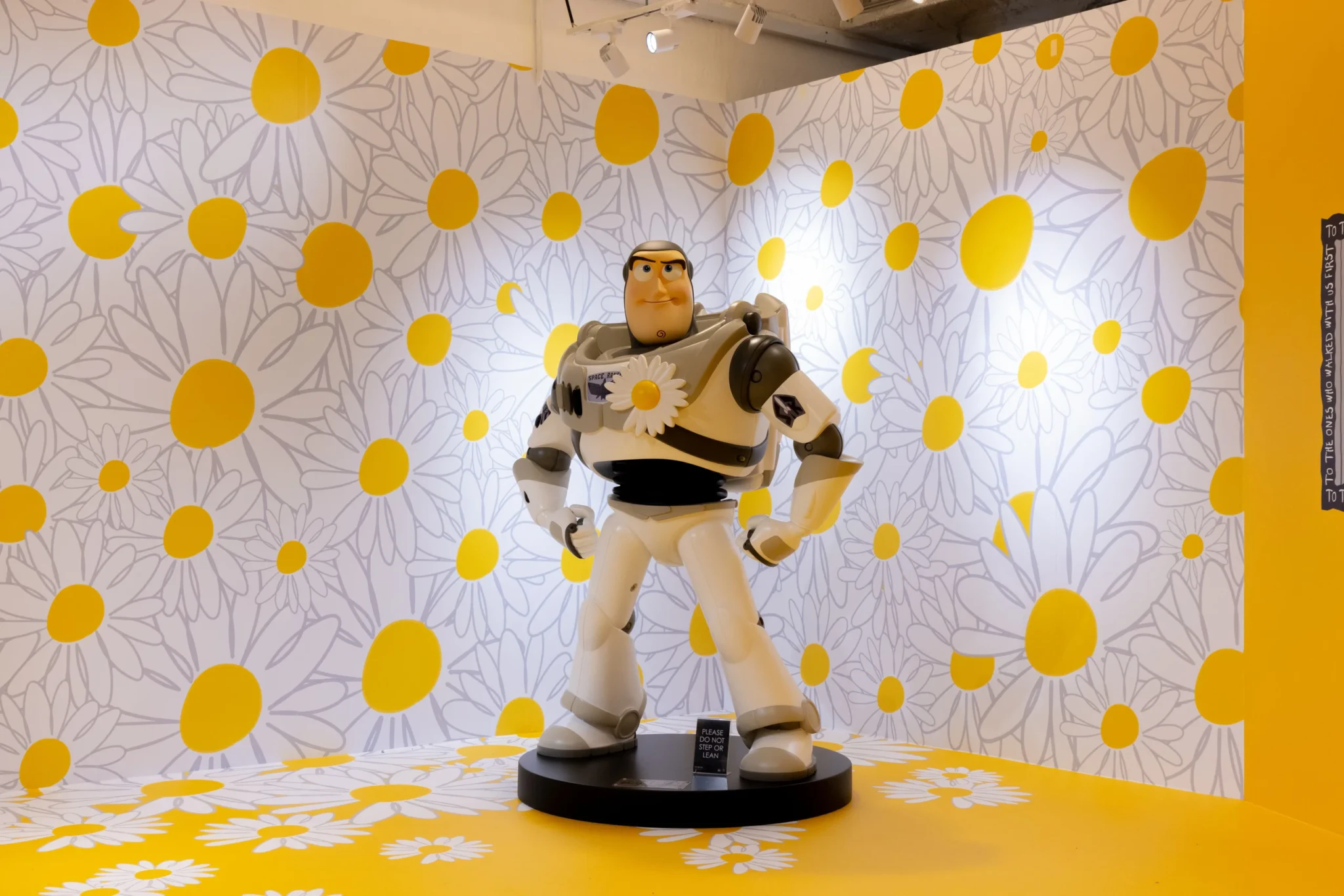 A Buzz Lightyear figure standing in front of a yellow daisy-patterned wall
