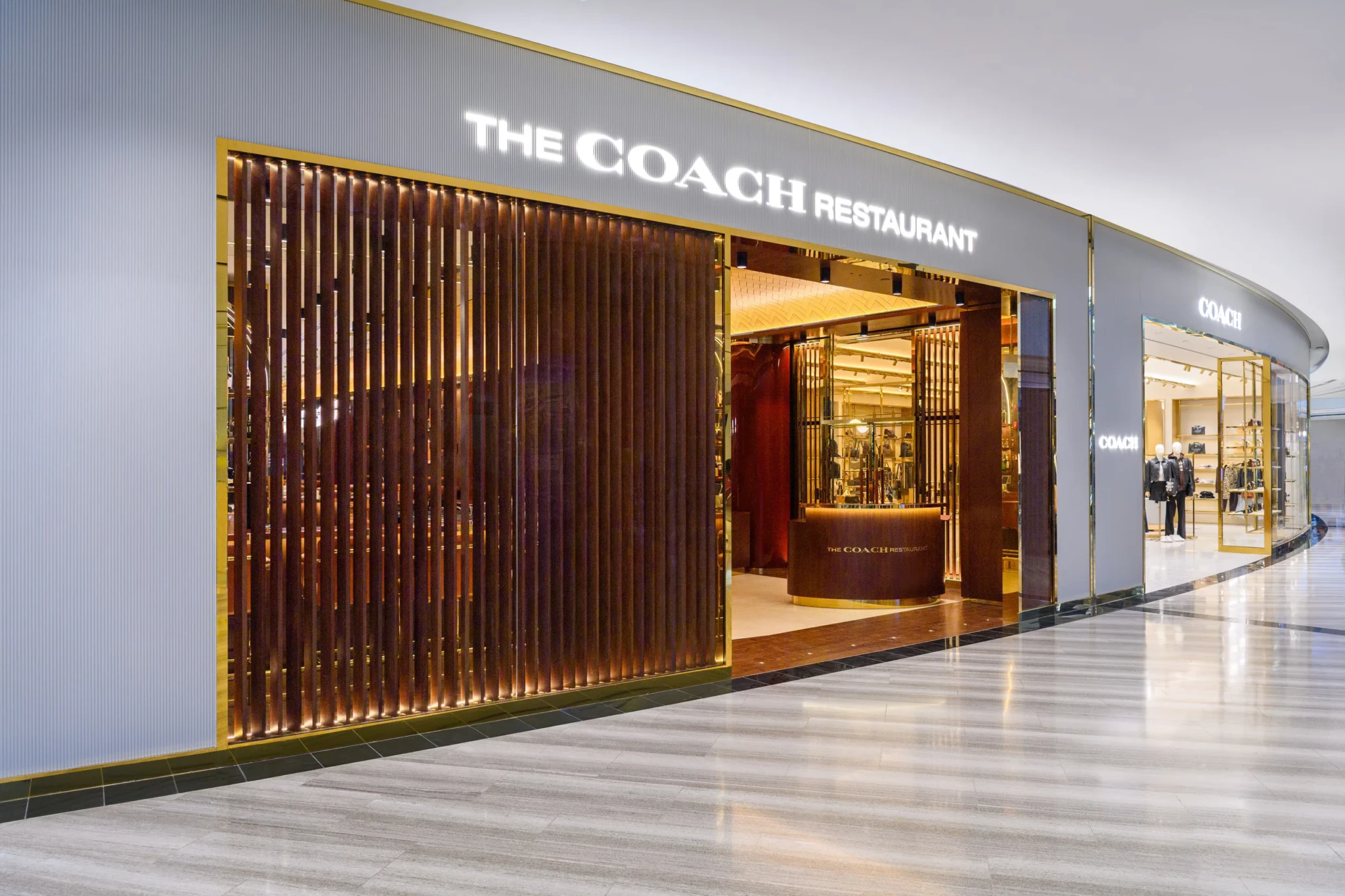 The entrance of The Coach Restaurant at Jewel Changi Airport, with a wooden slatted facade and lit signage beside the Coach boutique