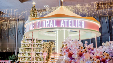 The Floral Atelier carousel-style installation with pink and white floral arrangements and a decorated Christmas tree at The Christmas Atelier