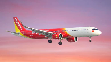 A red and white Vietjet Air aircraft in flight against a sunset sky