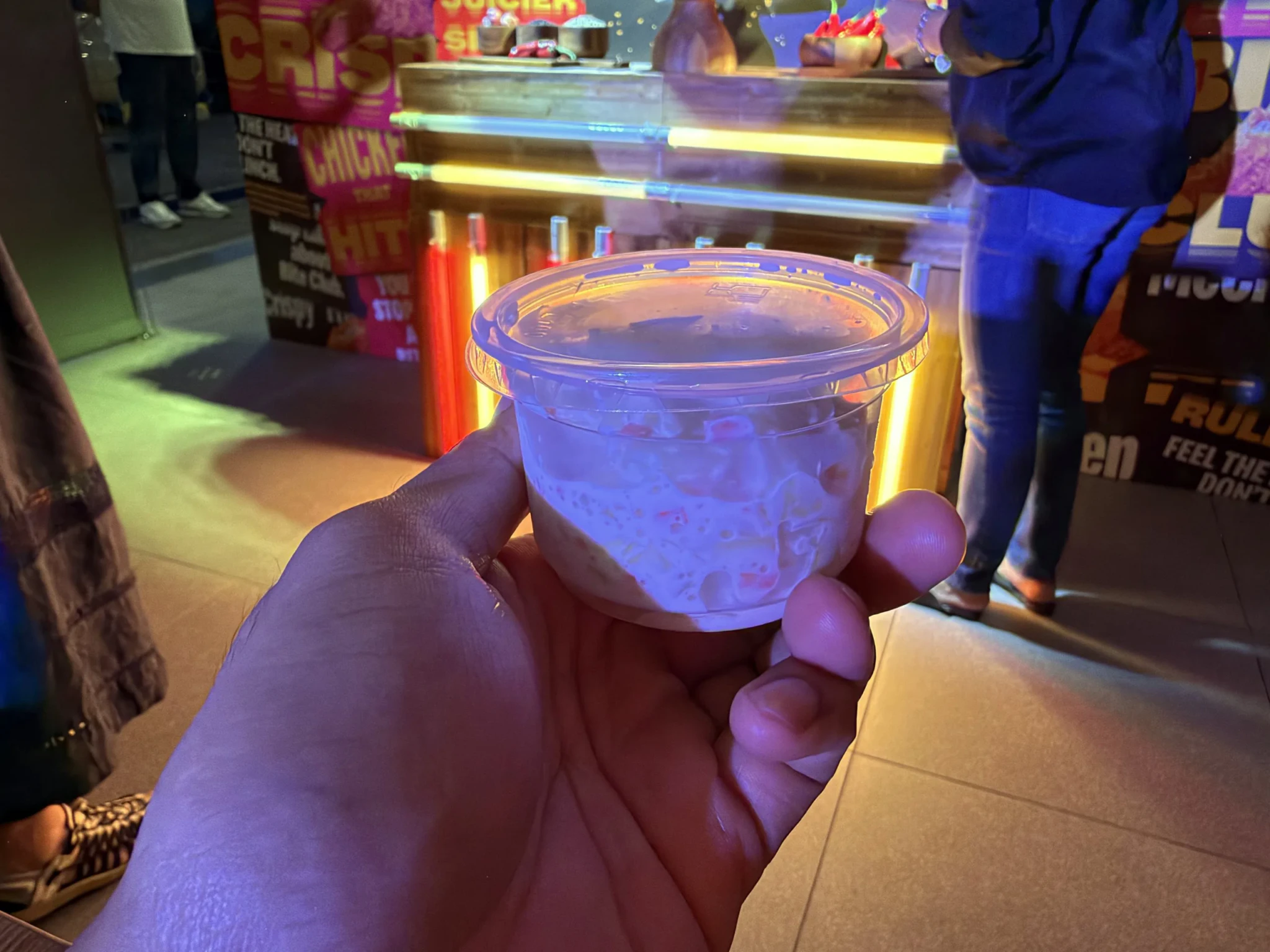 A hand holding a clear cup of coleslaw at the Bite Club launch