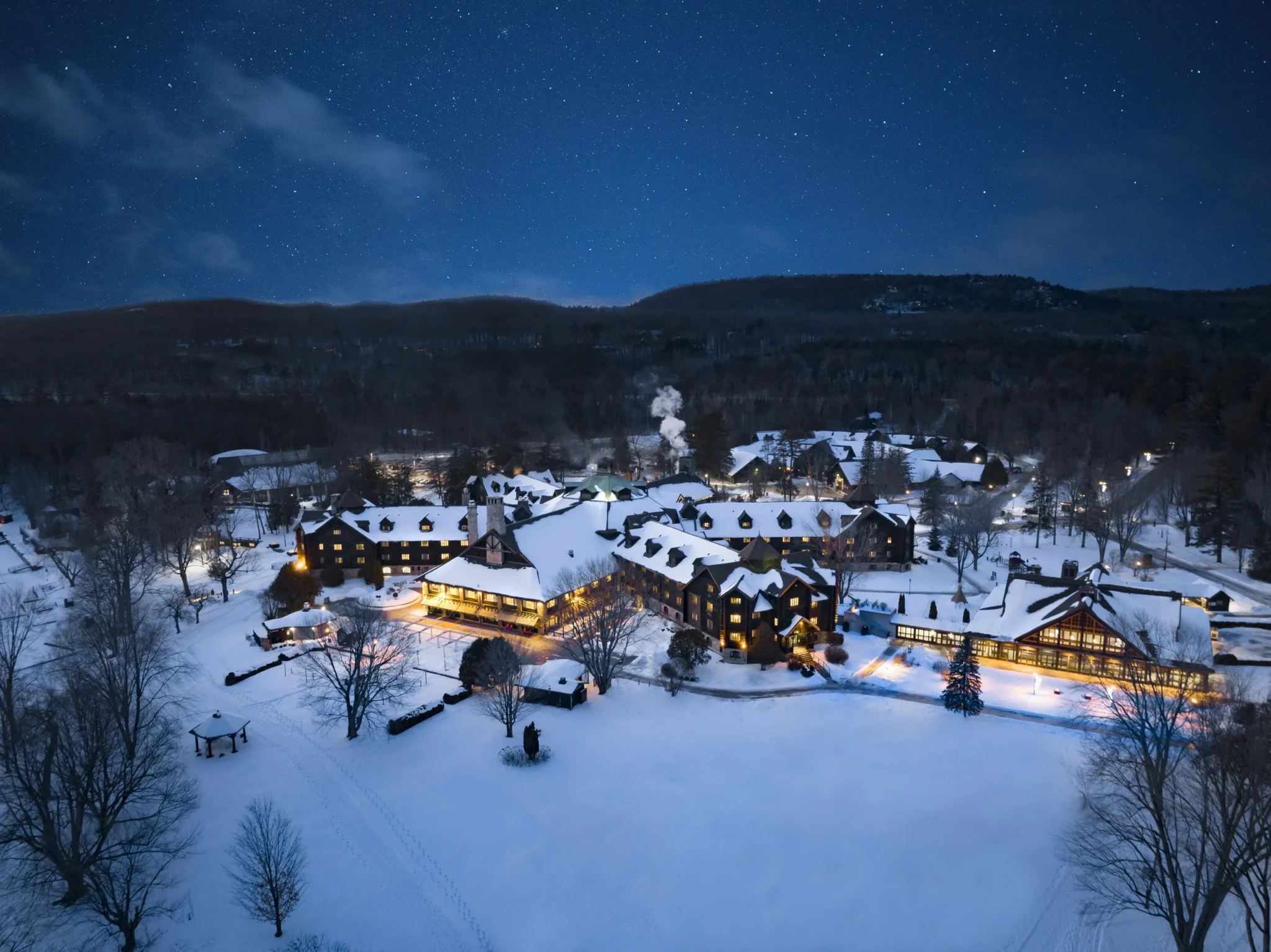 Aerial night view of Fairmont Le Château Montebello with its lodge buildings under fresh snow and a starry sky
