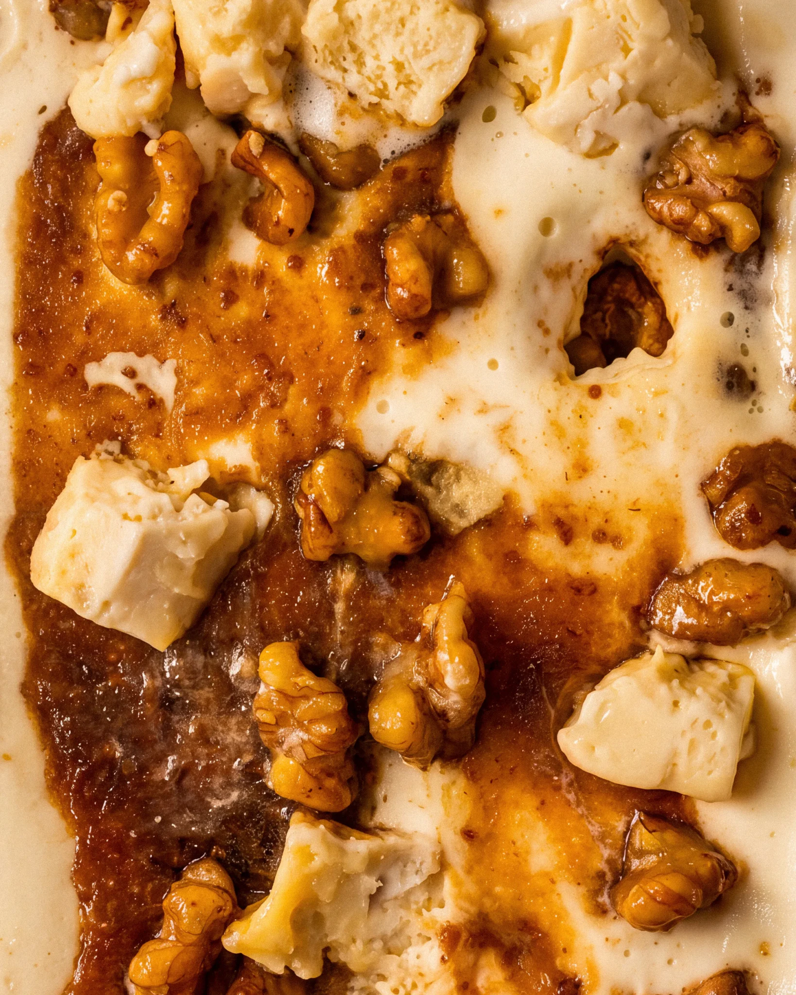 Close-up of Eazy Brie-zy gelato with chunks of brie, caramelised walnuts and a golden honey swirl in the tub