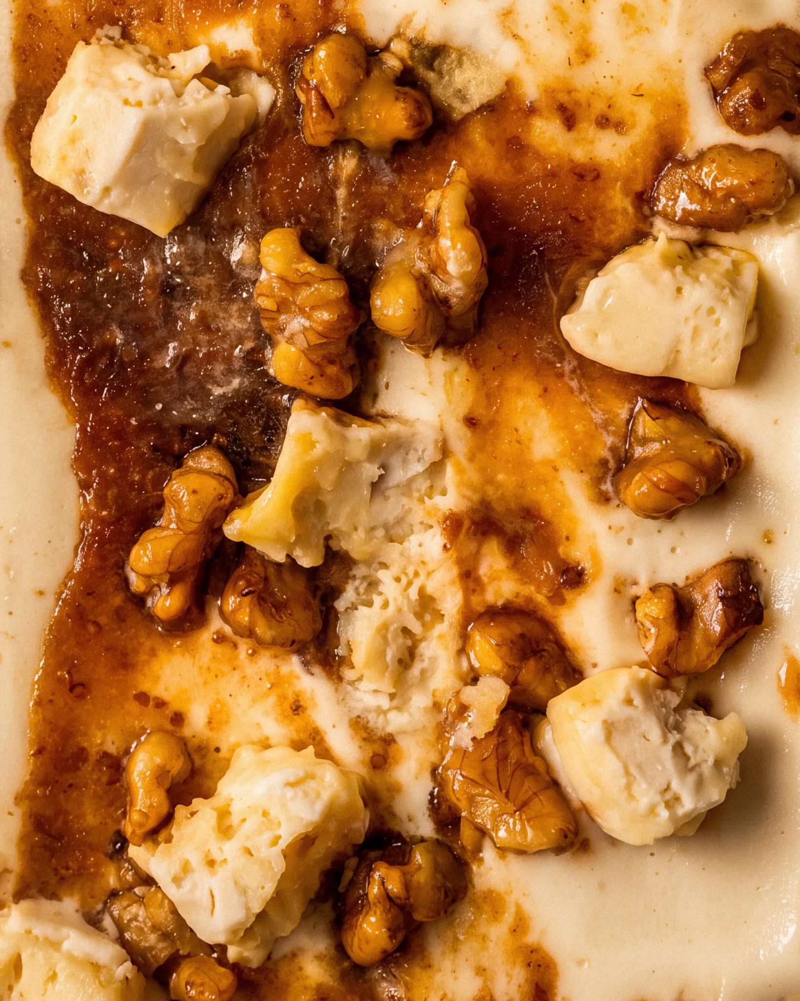 Close-up of the Eazy Brie-zy Honey Brie Cheesecake gelato, showing chunks of brie and caramelised walnuts in a honey-amber sauce.
