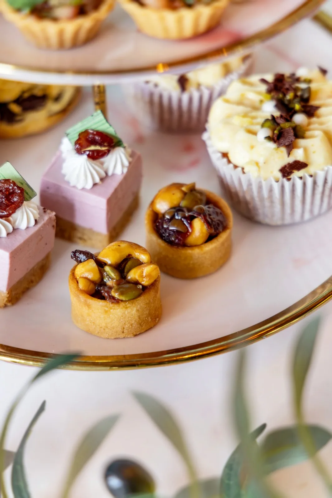 Caramelised cashew nut tarts, a berry cheesecake and an orange ginger cupcake on a tiered stand