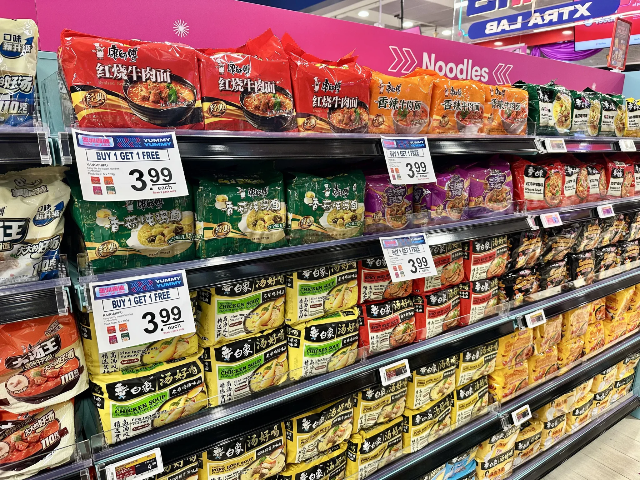 Kang Shi Fu instant noodles on a supermarket shelf under a Noodles sign with Buy 1 Get 1 Free price tags