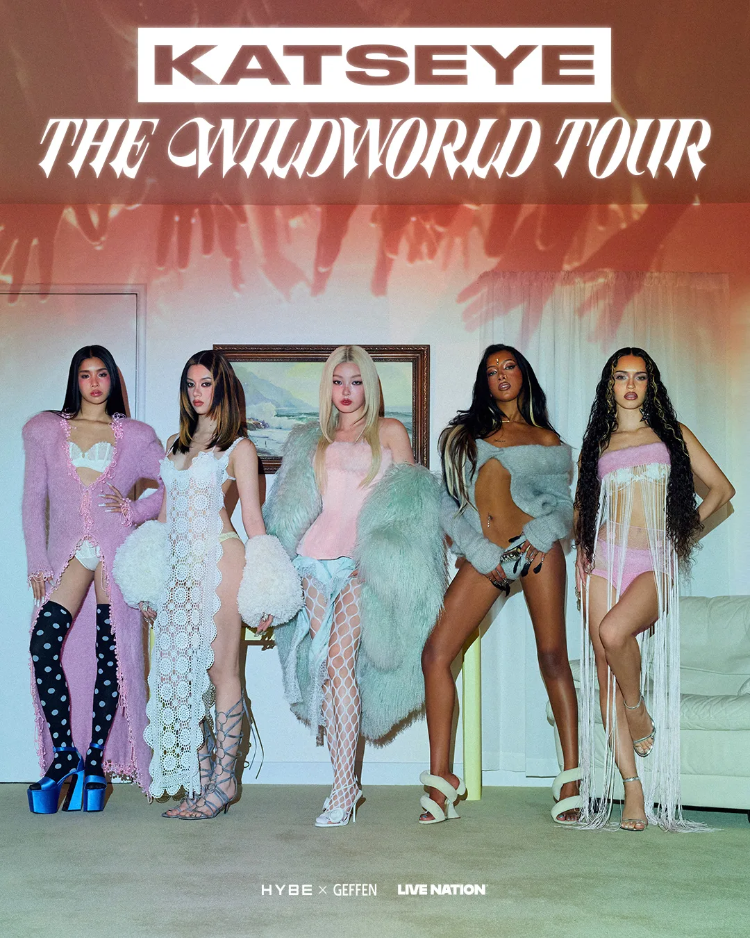 Promotional poster for KATSEYE's The Wildworld Tour showing the group posed together in pastel fur, fringe and fishnet styling in a retro-styled room