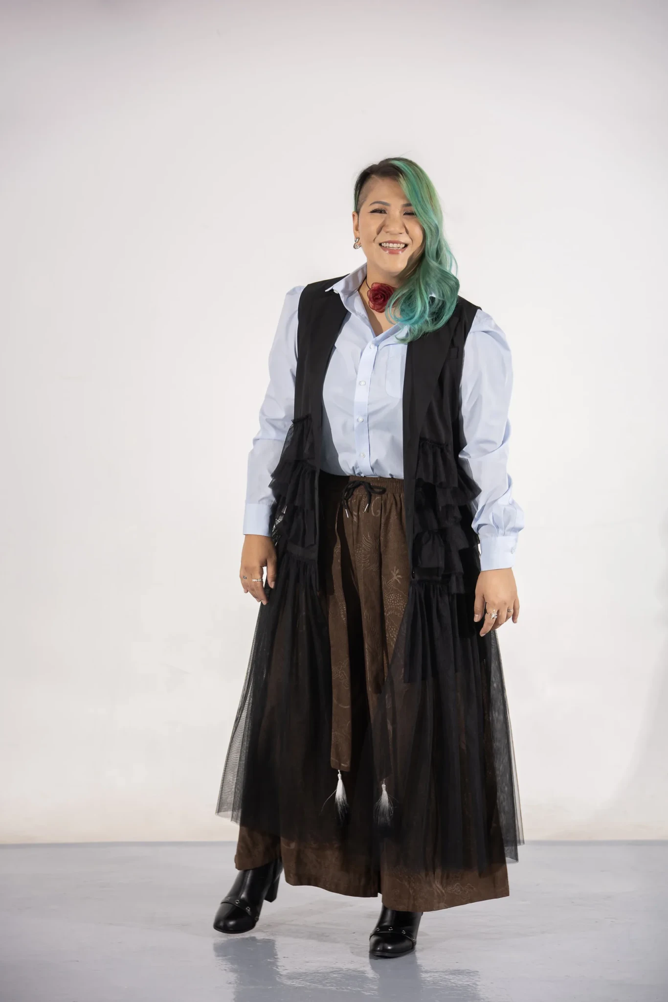 Calin Wong of MICappella in a black tulle vest and red rose choker against a white backdrop