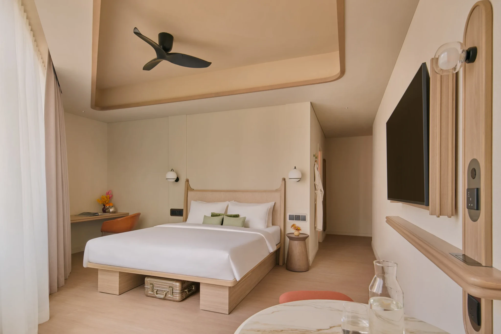 An APT. Urban room with a king bed, black ceiling fan, wall-mounted TV and wooden desk