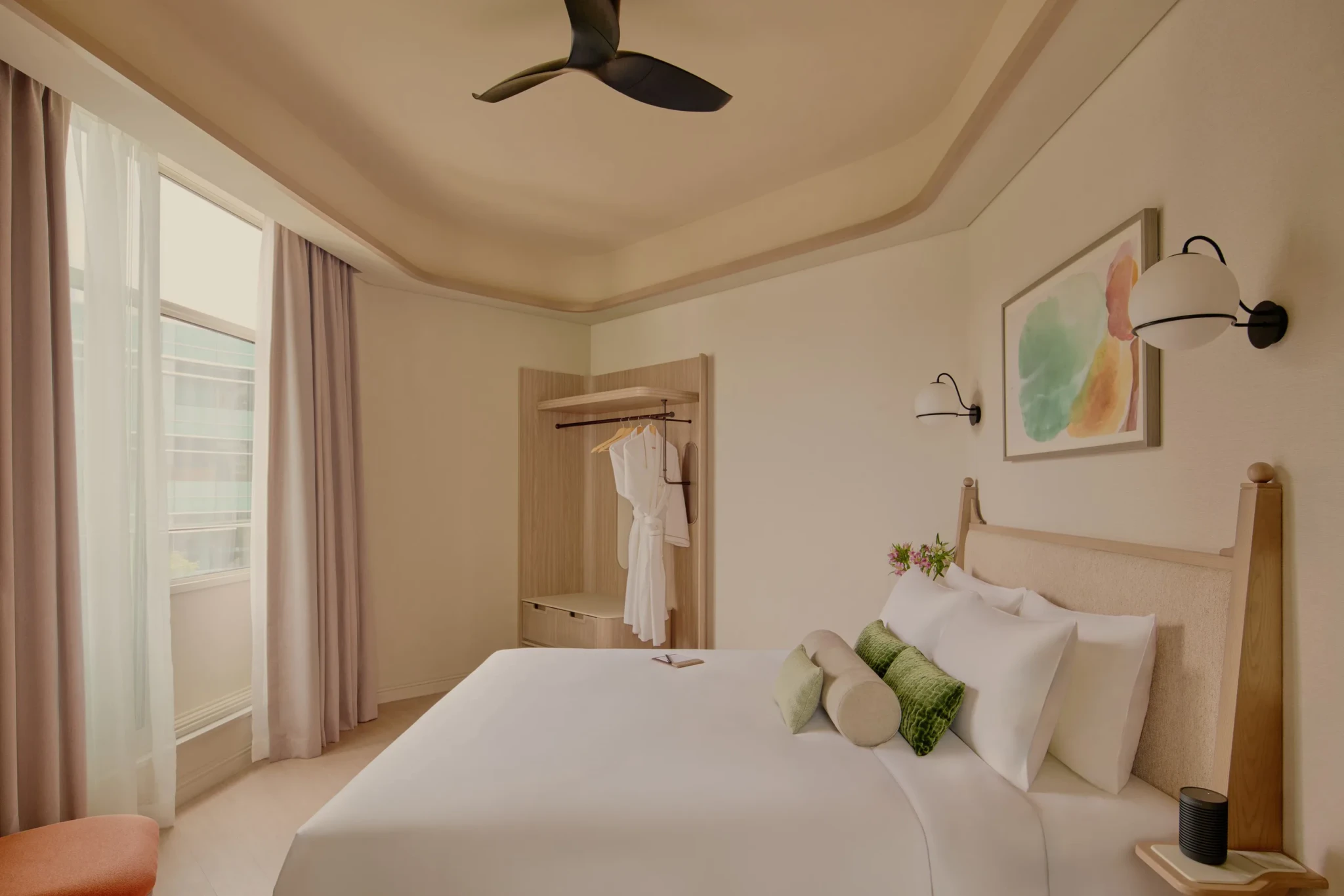 A Canning Suite bedroom with a king bed, green cushions, globe reading lamps, watercolour artwork and a ceiling fan